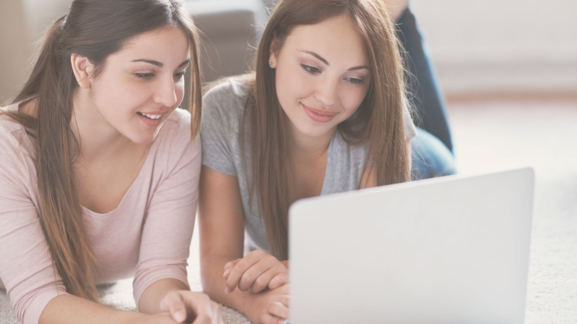 Deux jeunes souriantes devant un ordinateur à la recherche d'un logiciel pour leur entreprise.